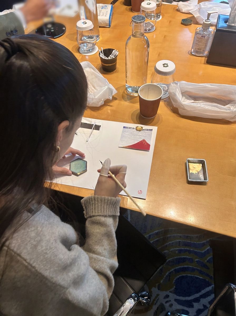 A participant applying gold along the seam of a repaired ceramic piece with a fine brush